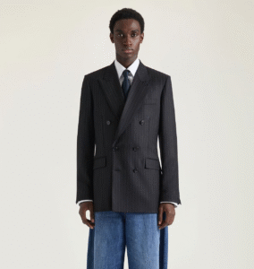 Veste croisée à rayures Givenchy par Sarah Burton associée à une chemise blanche et cravate, avec un jean brut large retroussé et bottines noires robustes