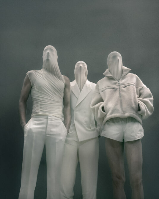 Trois silhouette LGN FW26 en costume blanc avec headpiece sombre évoquant l’esthétique Alien.