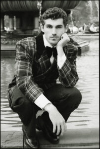 Portrait éditorial masculin en noir et blanc photographié à New York par Elys Berroteran, hommage à Ralph Lauren, avec Anselmo Menéndez devant une fontaine à Central Park dans un tailoring à carreaux élégant.