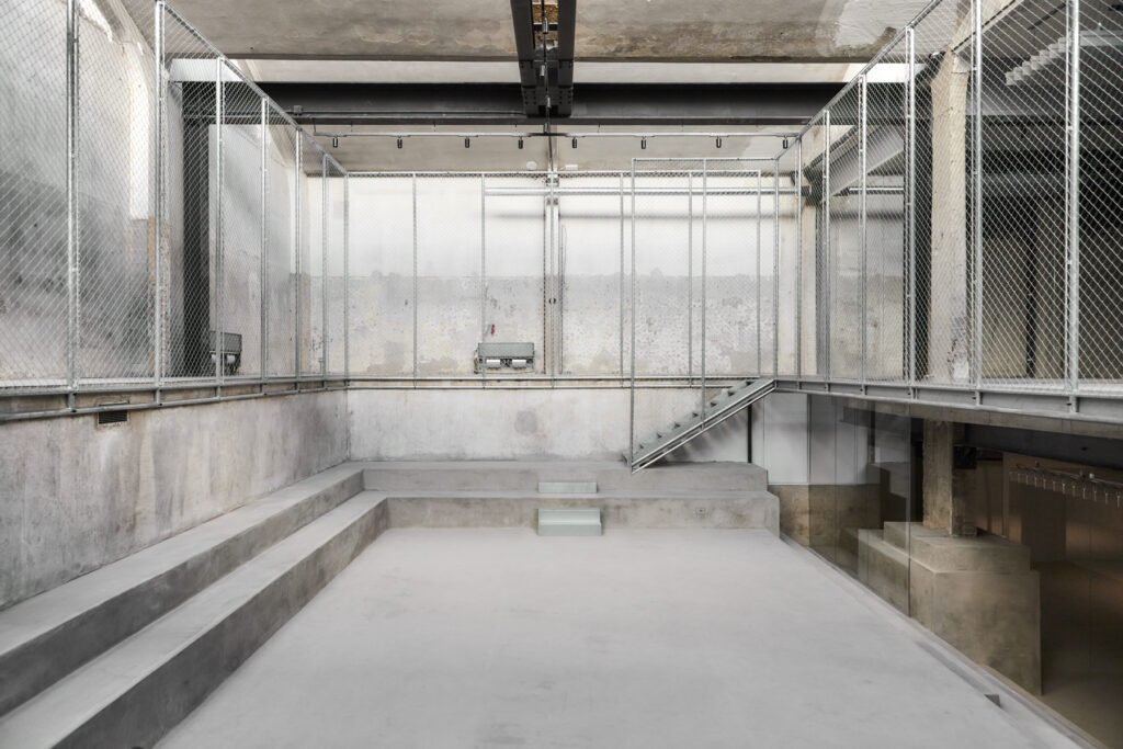 Industrial stairwell with concrete steps and metal chain-link fencing surrounding an open concrete space