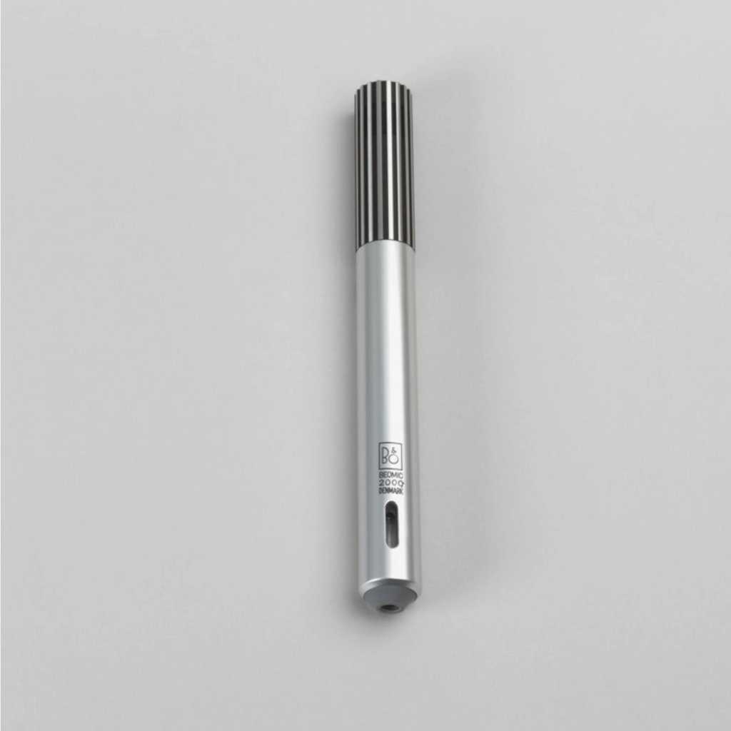 Slim silver microphone with a ribbed black grille on top, resting on a light gray surface.