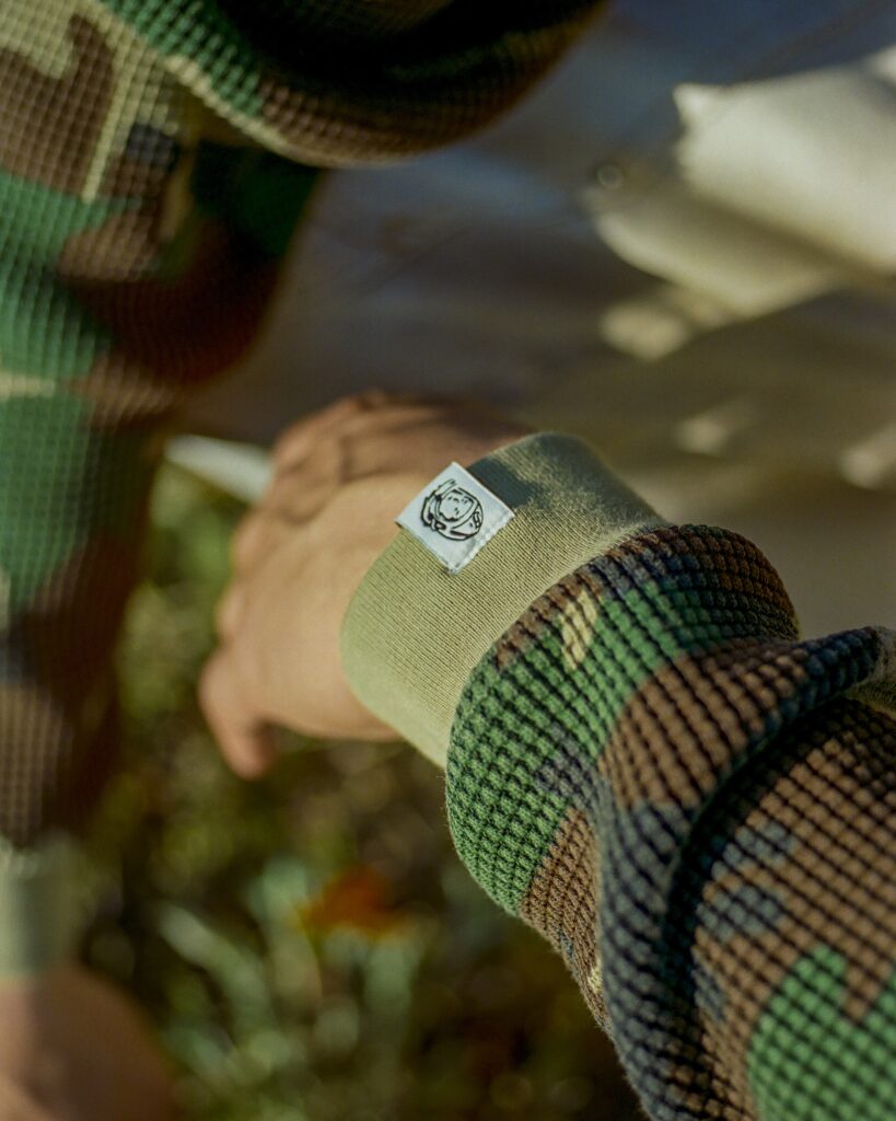 Close-up of a green-brown woven strap with a small white label showing a circular logo or icon.