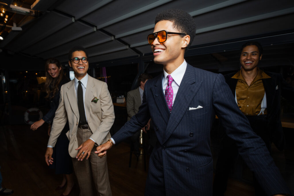 Group of well-dressed friends dancing and laughing at a party indoors.