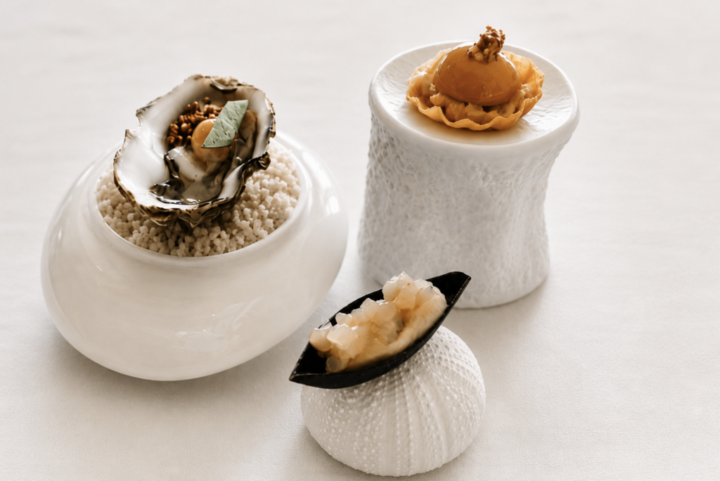 Composition d'amuse-bouches imaginés par le chef Ronan Fillatre au George's. Entre coquillages, textures minérales et céramiques blanches, les premières bouchées évoquent la rencontre entre l'océan, le végétal et la lumière de l'Île de Ré.
