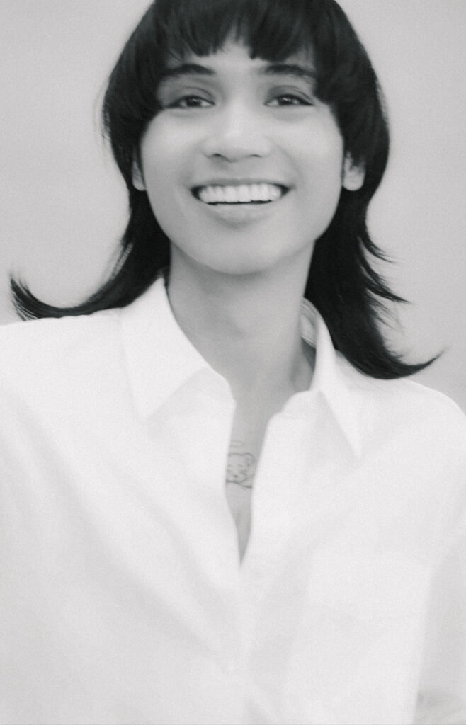 Black-and-white portrait of a smiling woman with short dark hair wearing a white shirt.