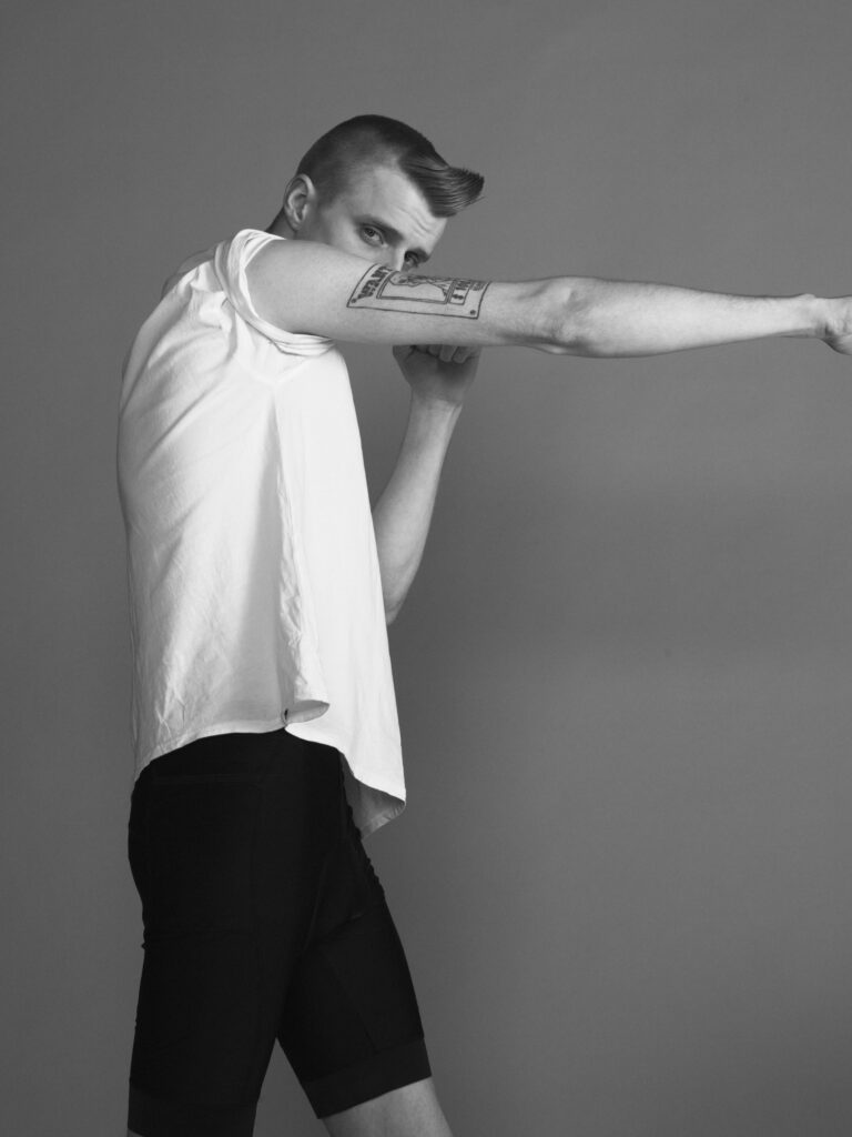 Black-and-white photo of a man in a white shirt punching forward with his extended right arm, looking toward the camera.