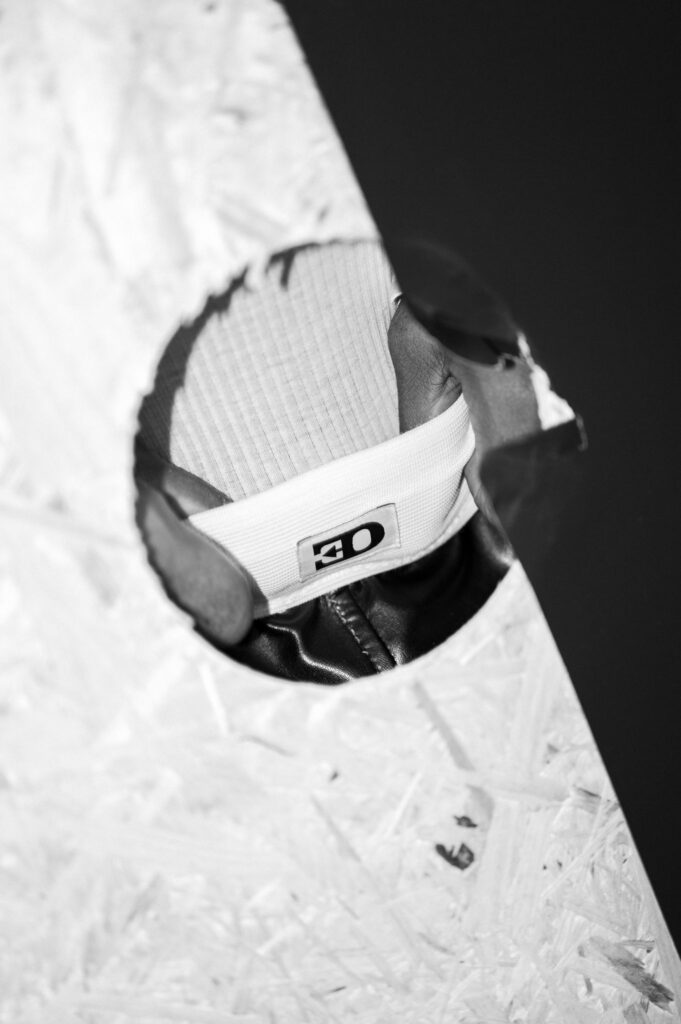 Close-up of a white sneaker peeking through a torn, textured surface; the tongue shows the number 40.