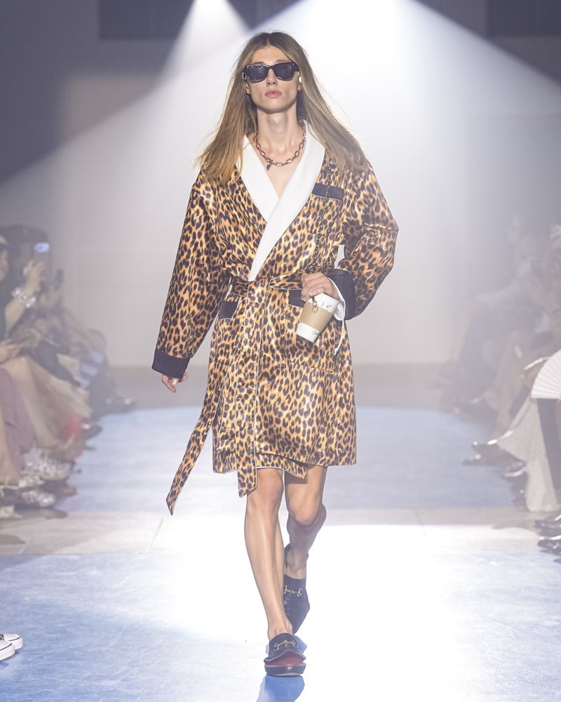 Silhouette doublet SS27 portant une robe imprimé léopard, des lunettes noires et un accessoire en forme de gobelet suspendu à une chaîne.